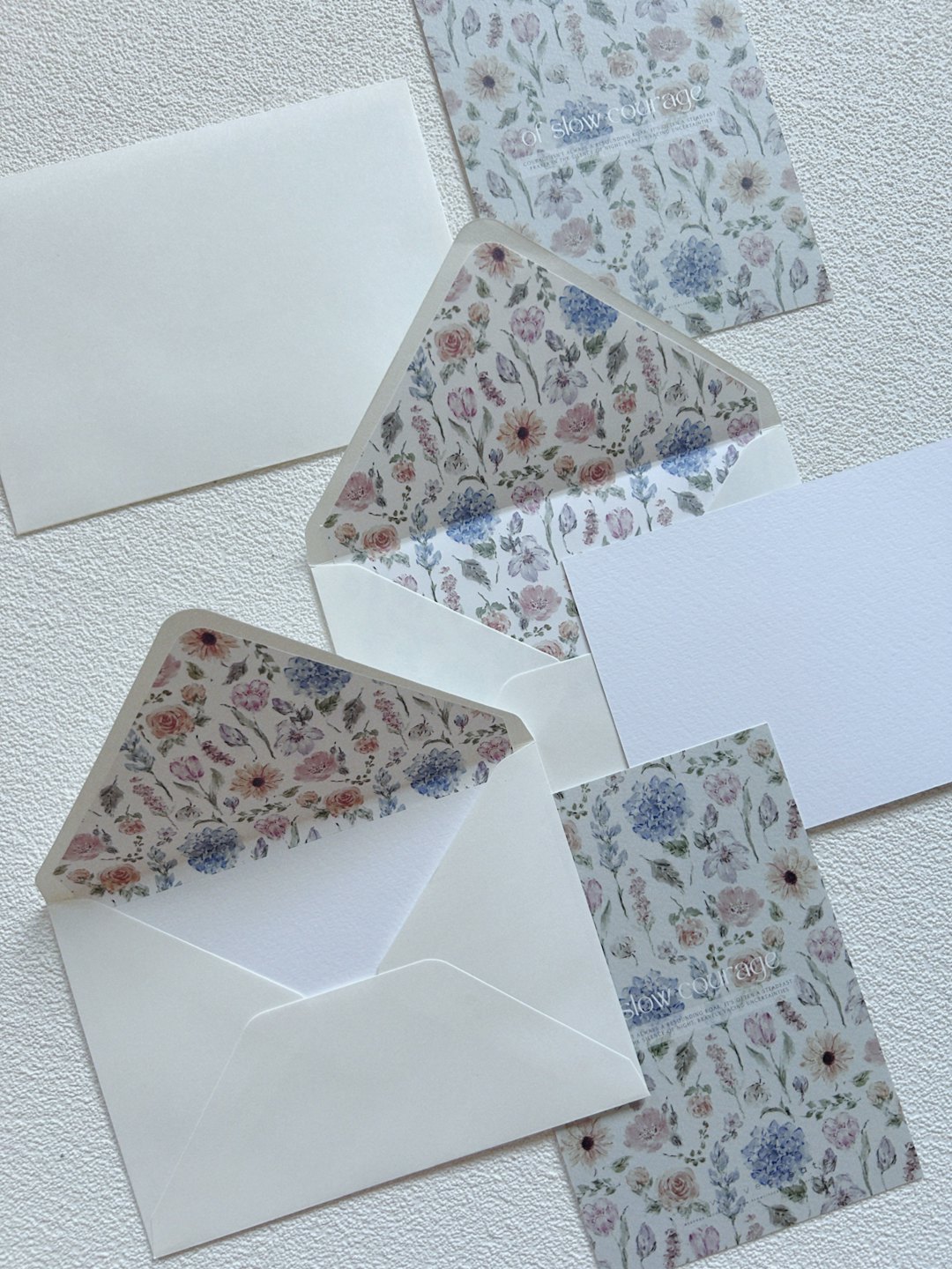 Elegant floral stationery and envelopes arranged on a grey surface.