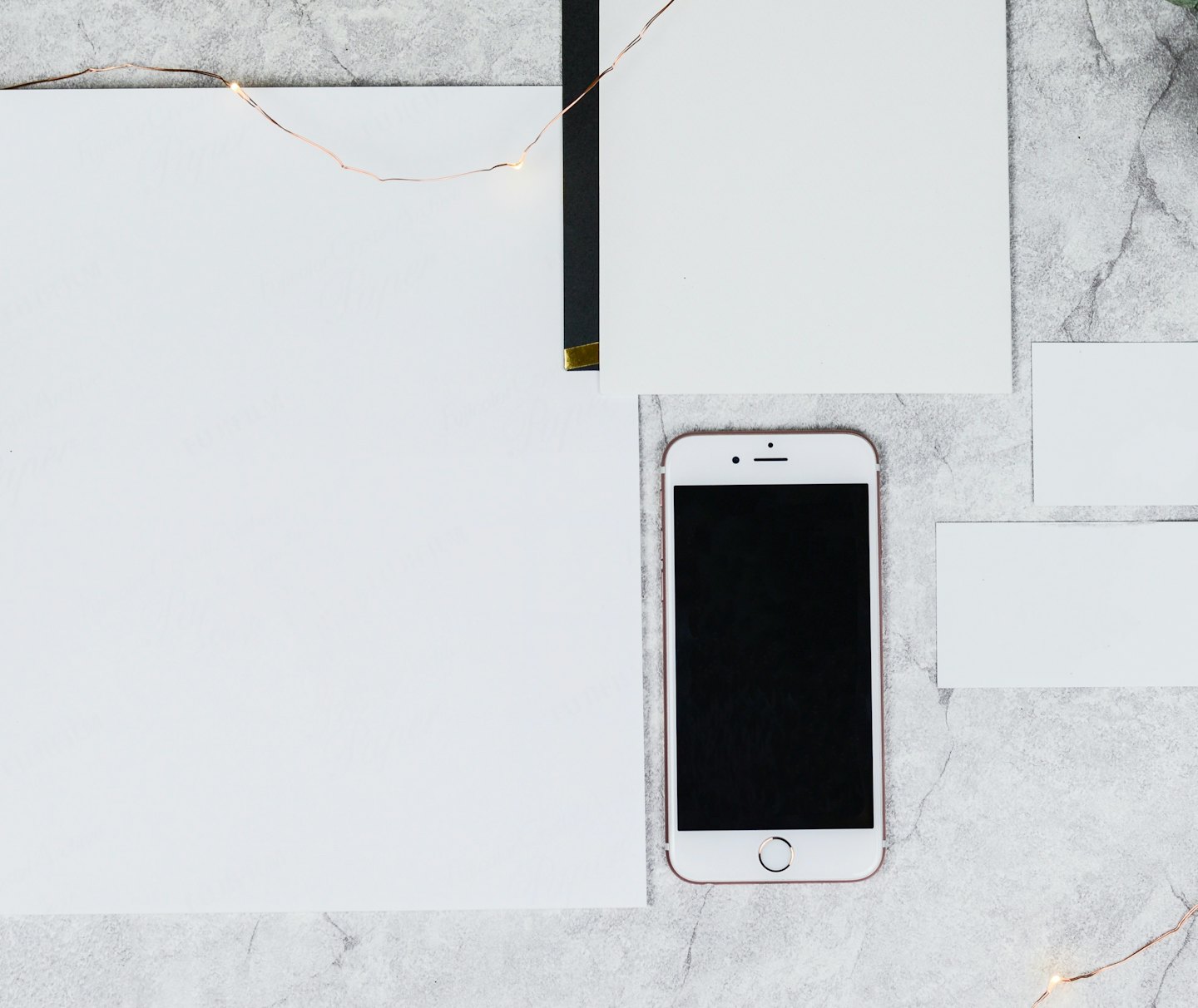 Stationery and a smartphone arranged on a marble surface.
